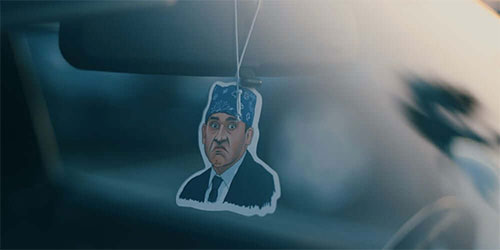 Michael Scott from Office character air freshener hanging on mirror in car